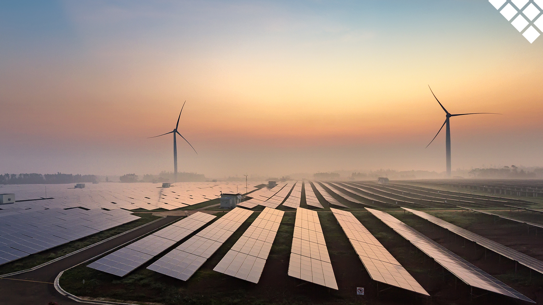 Beautiful sunrise with solar panels in foreground and wind turbines behind them