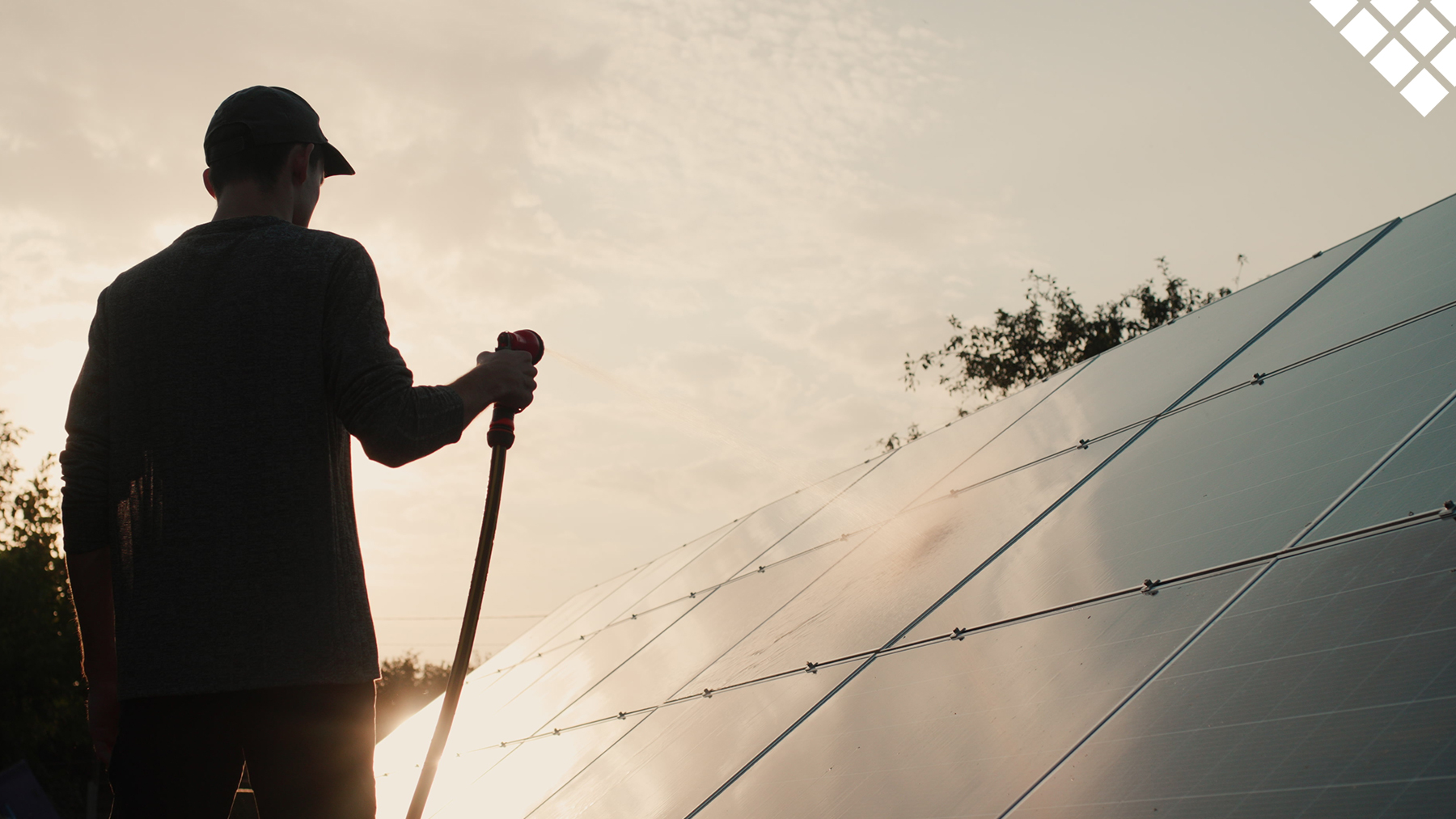 Guy spraying solar panels on roof with hose