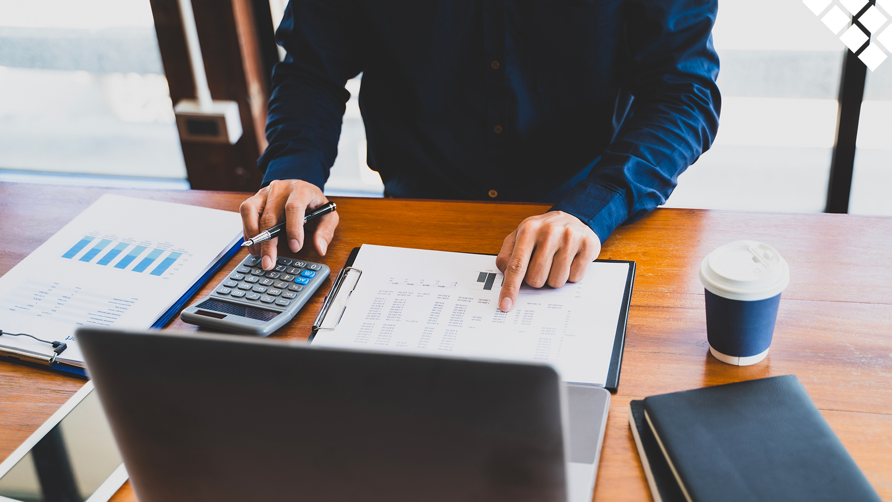 Man looking at charts and tax breaks in front of laptop on desk