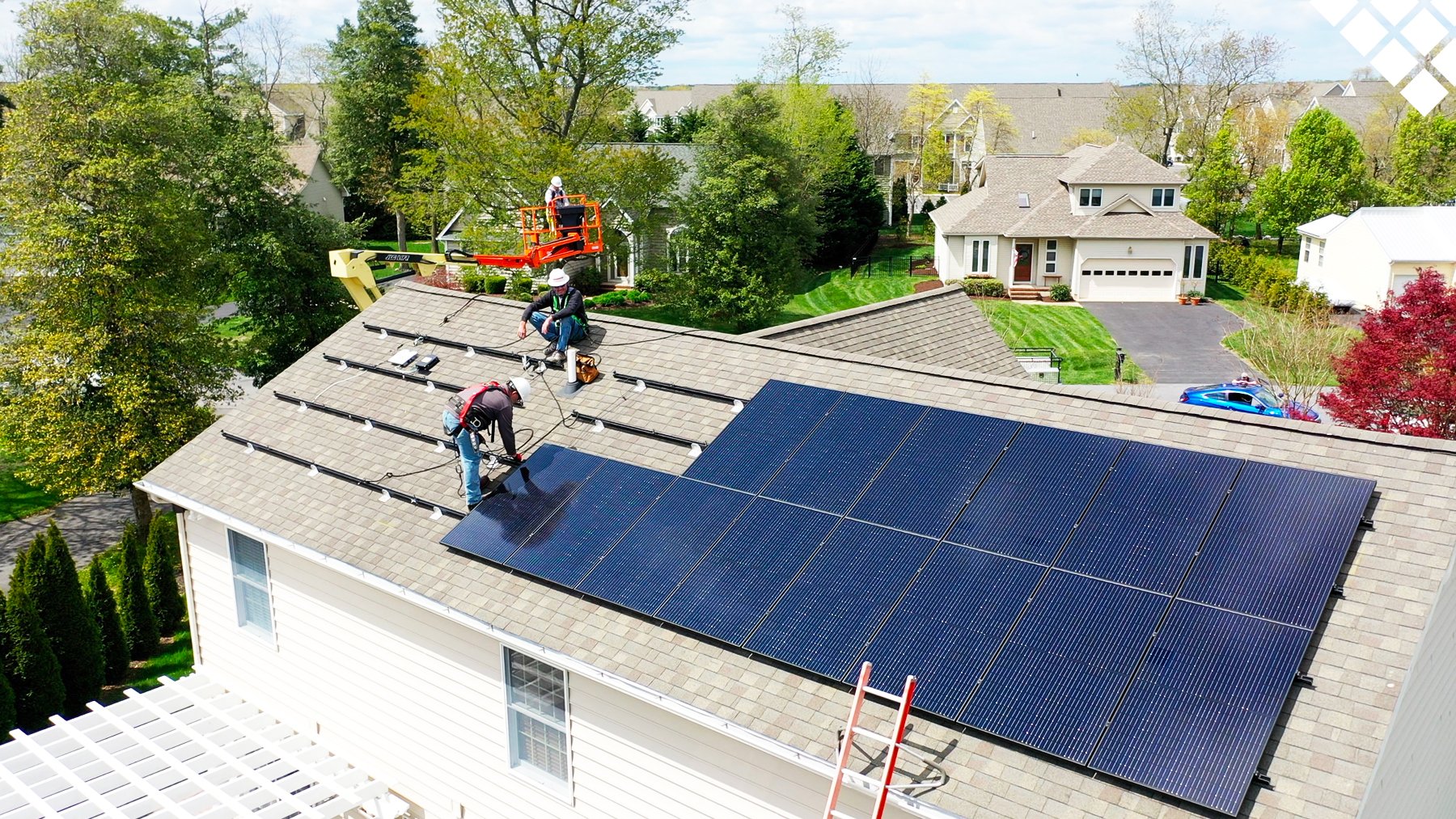 Workers installing solar panels on residential roof in neighborhood