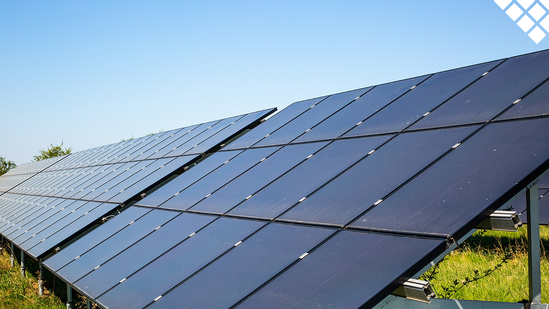 Commercial black solar panels in grass with blue sky