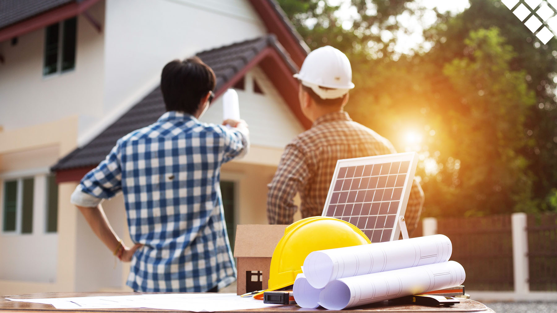 two men reviewing the roof of a home with a solar panel, blue prints, and a hard hat on the table in front of them